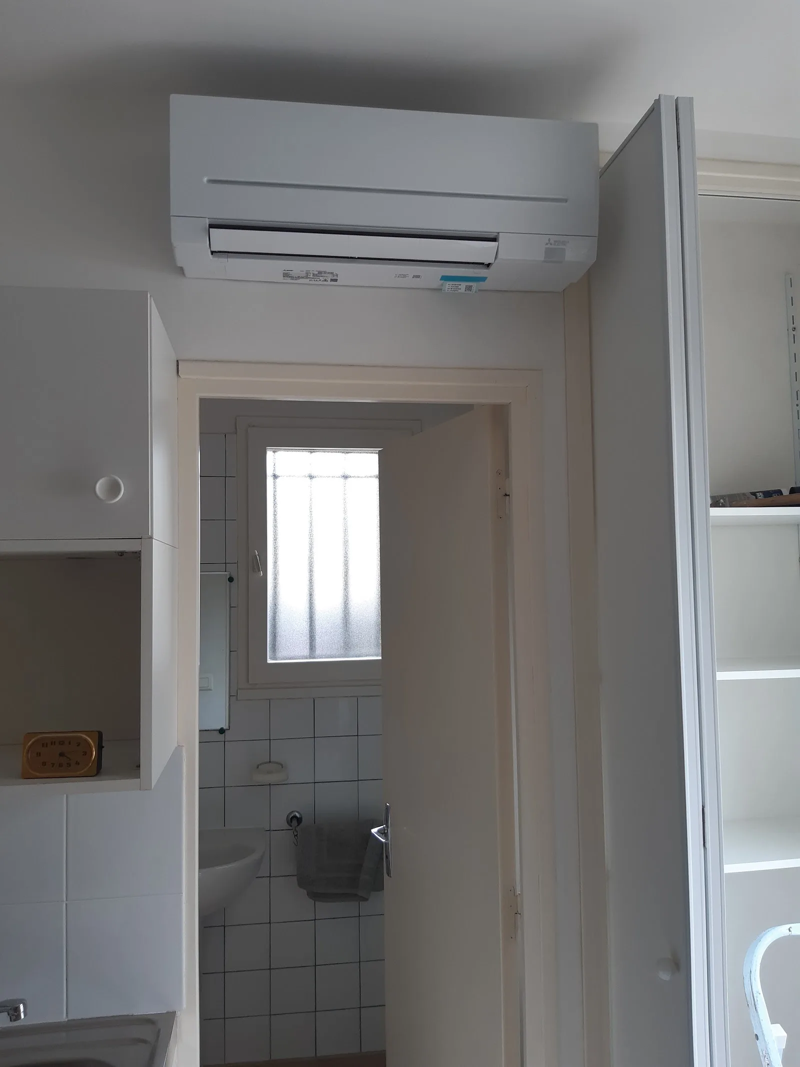 Split de climatisation posé au-dessus d'une porte dans une pièce à vivre
