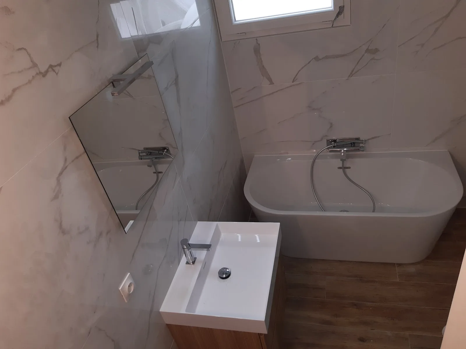 Salle de bain rénovée en carrelage effet marbre avec baignoire îlot